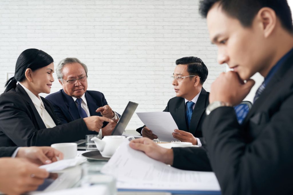 Grupo de empresarios asiáticos analizando documentos en una reunión de negocios.